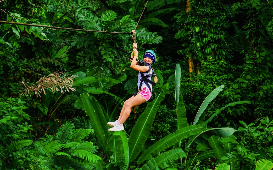 Zip lining through lush forest at Hanuman World, Thailand.