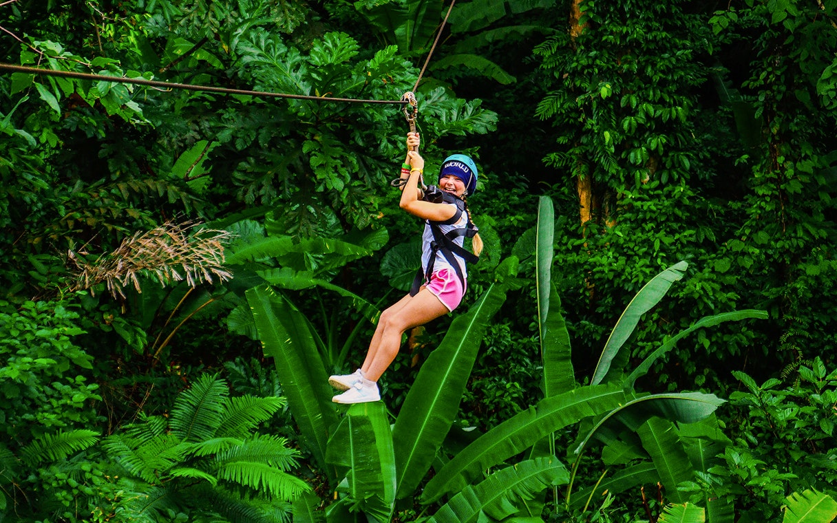 Zip lining through lush forest at Hanuman World, Thailand.
