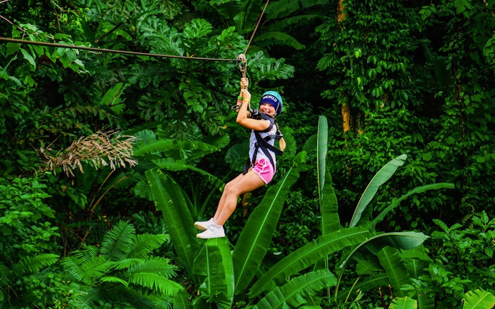 Zip lining through lush forest at Hanuman World, Thailand.