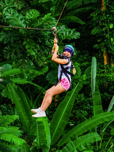 Zip lining through lush forest at Hanuman World, Thailand.