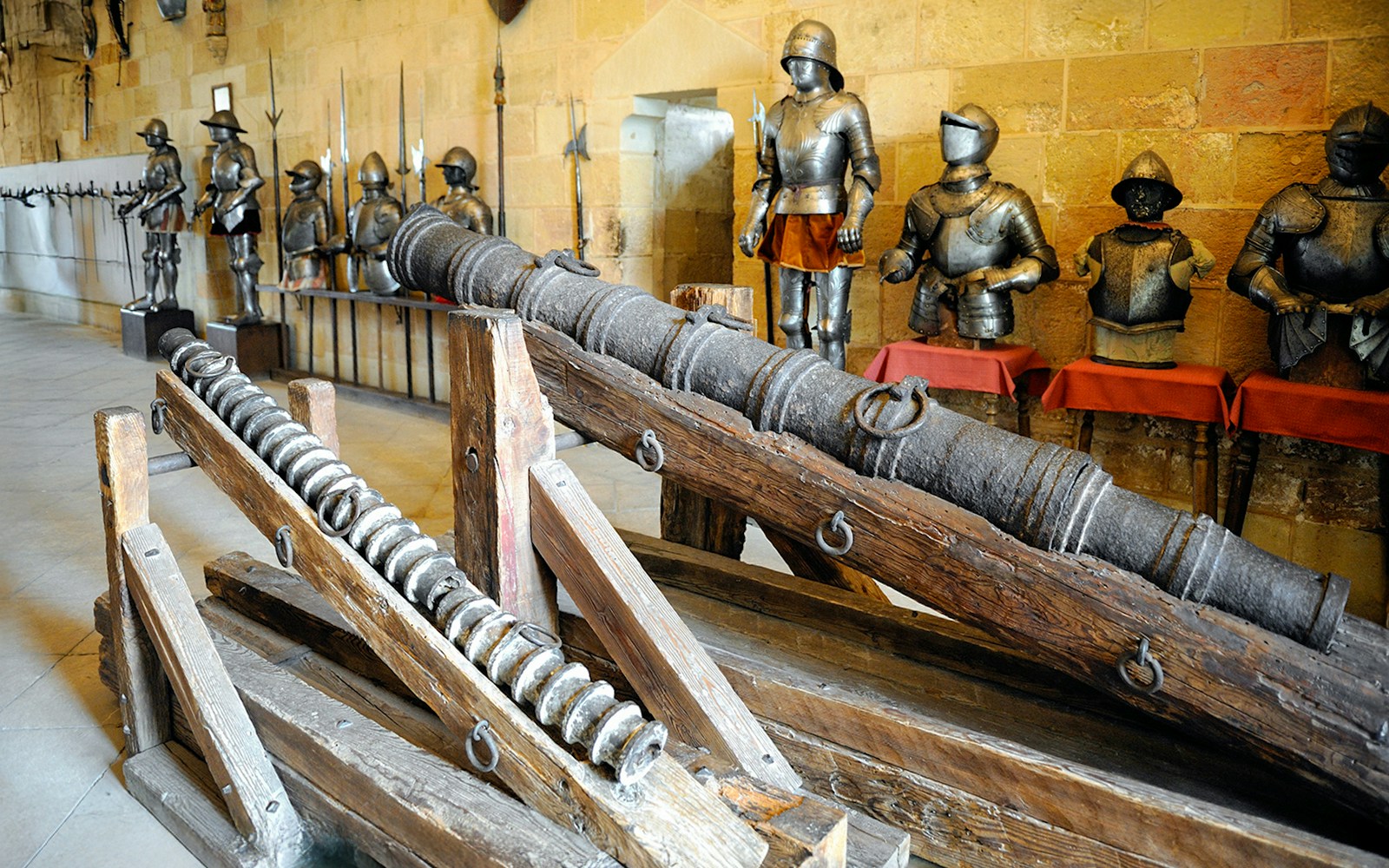 Segovia Alcazar armoury with medieval cannons and suits of armor displayed.