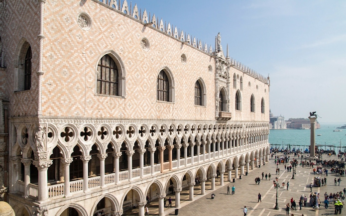 Doge's Palace facade with tourists in St. Mark's Square, Venice, near the waterfront.