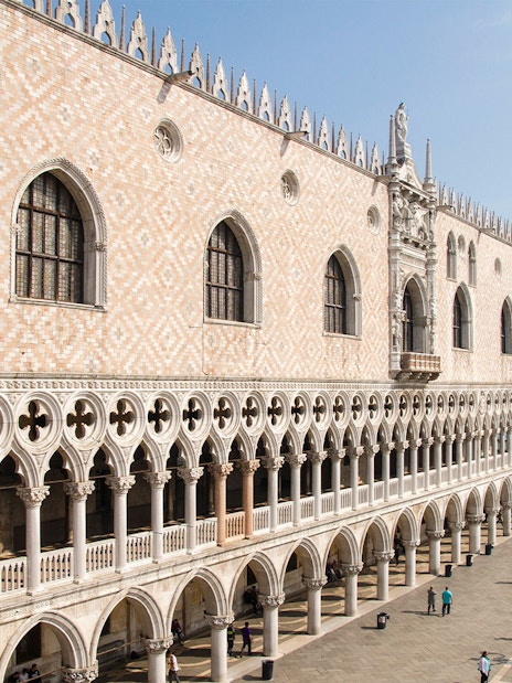 Doge's Palace facade with tourists in St. Mark's Square, Venice, near the waterfront.