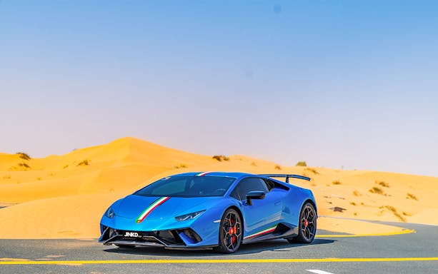Blue supercar on desert road during Dubai self-drive tour.