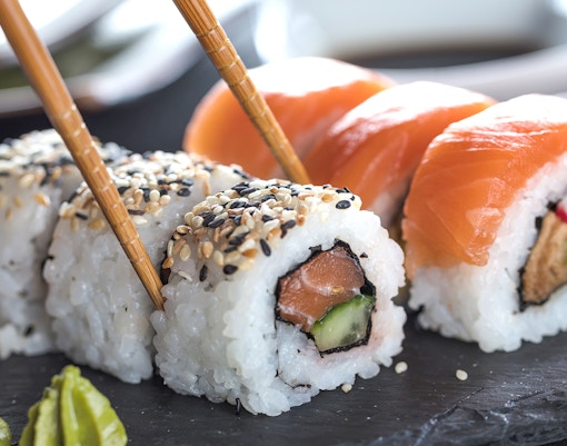 Sushi rolls with salmon and sesame seeds on a slate plate