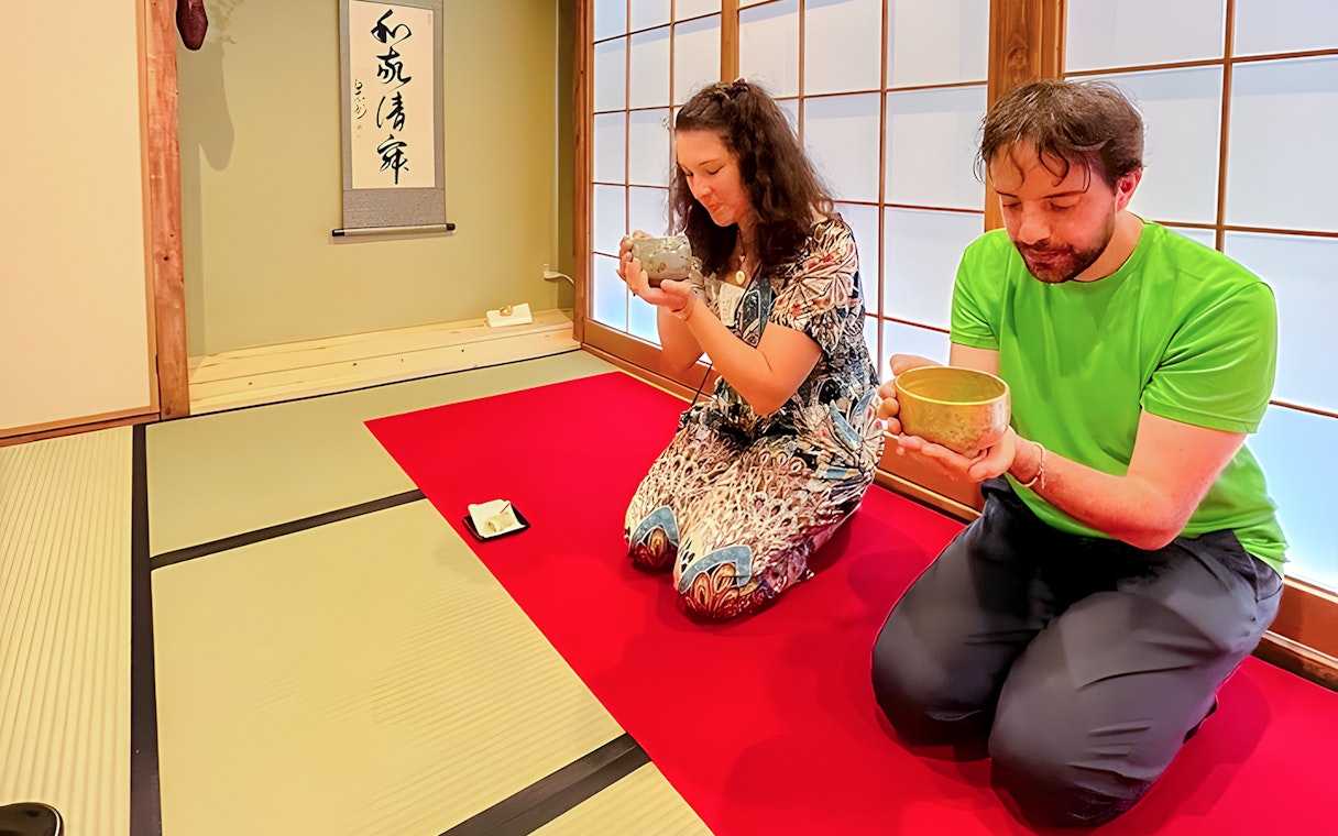 Couple enjoying matcha tea ceremony in traditional Japanese room, Osaka.