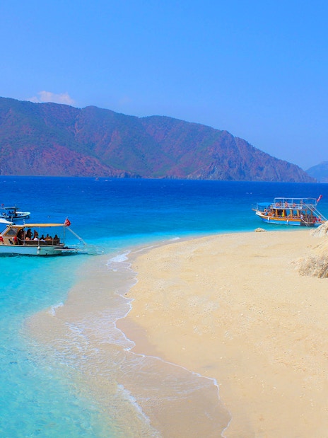 Boats anchored near Suluada Island's sandy beach, Antalya coast.