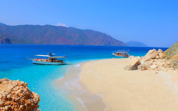 Boats anchored near Suluada Island's sandy beach, Antalya coast.