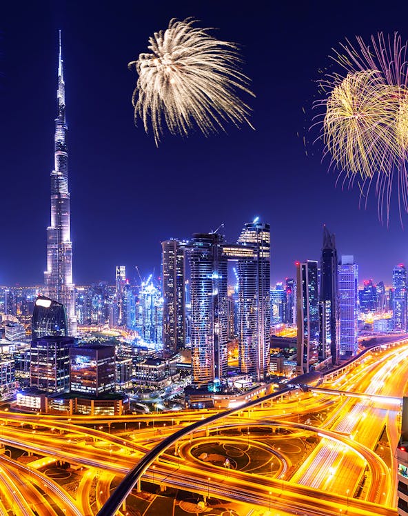 Dubai skyline with illuminated skyscrapers and fireworks at night, United Arab Emirates celebration.