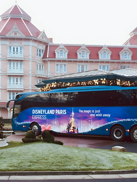 Disneyland Paris Express bus parked in front of a hotel, ready for round-trip to Paris.