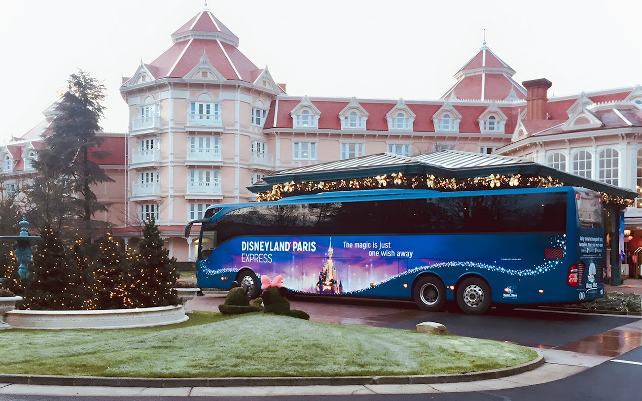 Disneyland Paris Express bus parked in front of a hotel, ready for round-trip to Paris.