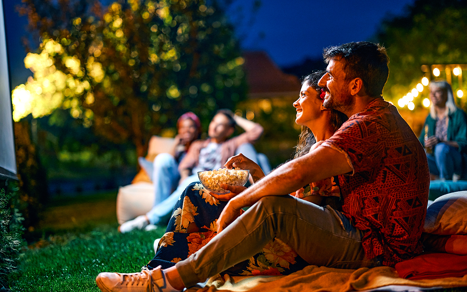 Couple enjoying popcorn at an outdoor movie screening.