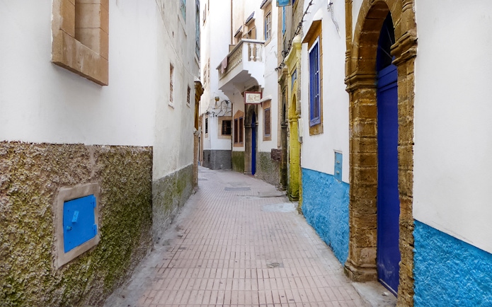 Narrow alleyway in Essaouira with blue doors and whitewashed walls.