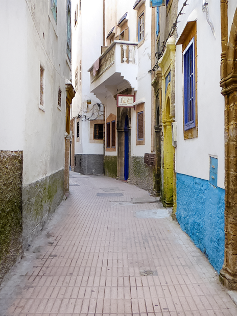 Narrow alleyway in Essaouira with blue doors and whitewashed walls.