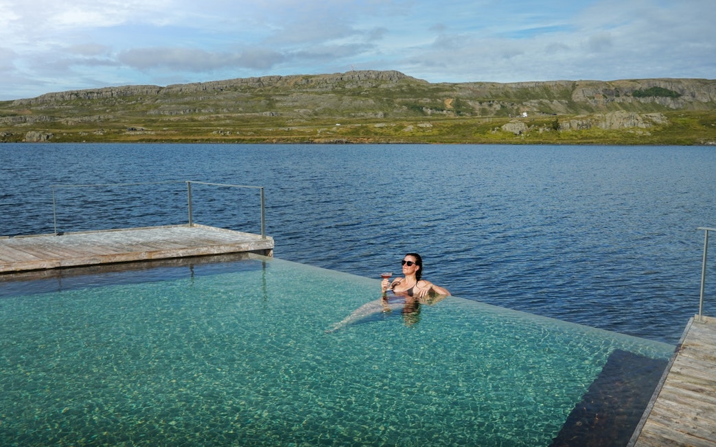 Person relaxing in Vök Baths infinity pool overlooking Lake Urriðavatn, Egilsstaðir.