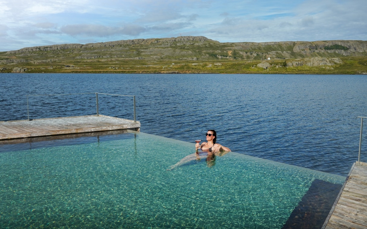 Person relaxing in Vök Baths infinity pool overlooking Lake Urriðavatn, Egilsstaðir.