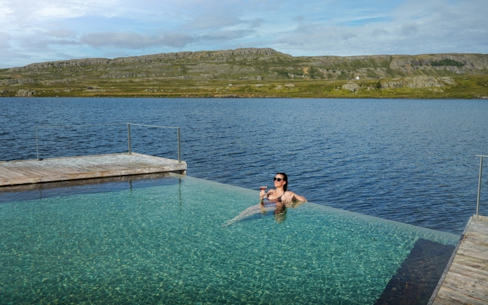 Person relaxing in Vök Baths infinity pool overlooking Lake Urriðavatn, Egilsstaðir.