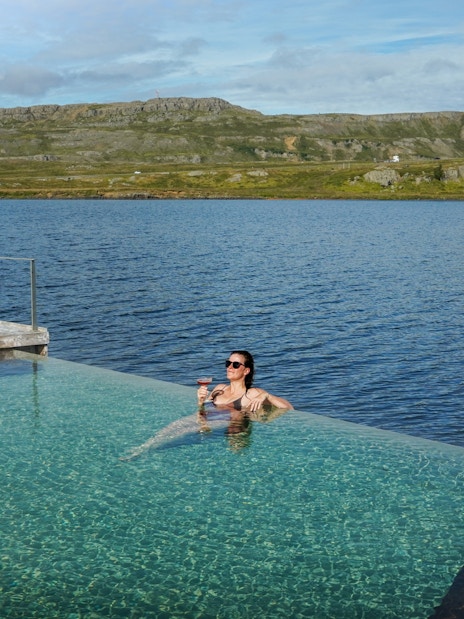 Person relaxing in Vök Baths infinity pool overlooking Lake Urriðavatn, Egilsstaðir.