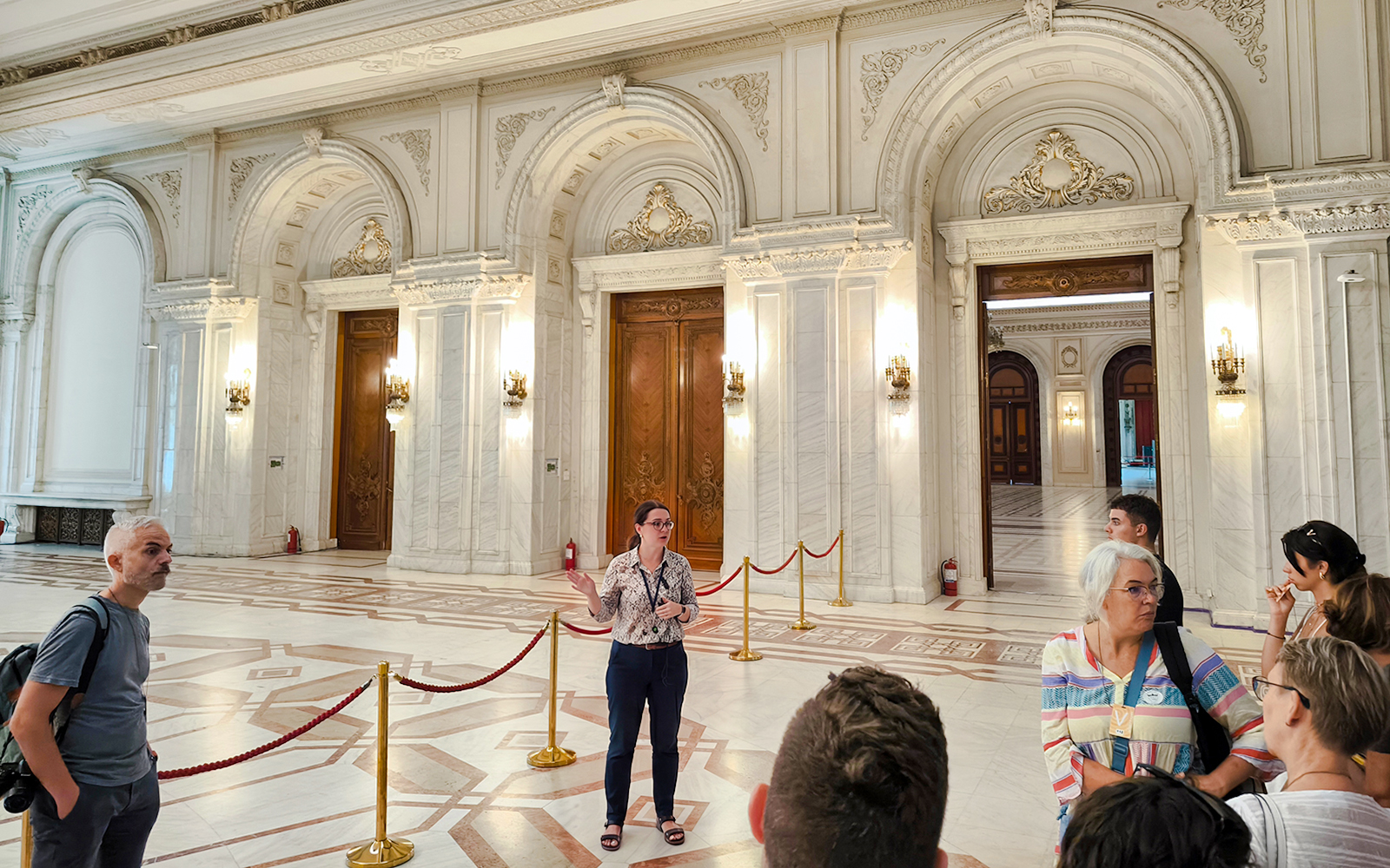 Tour guide explaining inside the ornate hall of the Palace of Parliament, Bucharest.