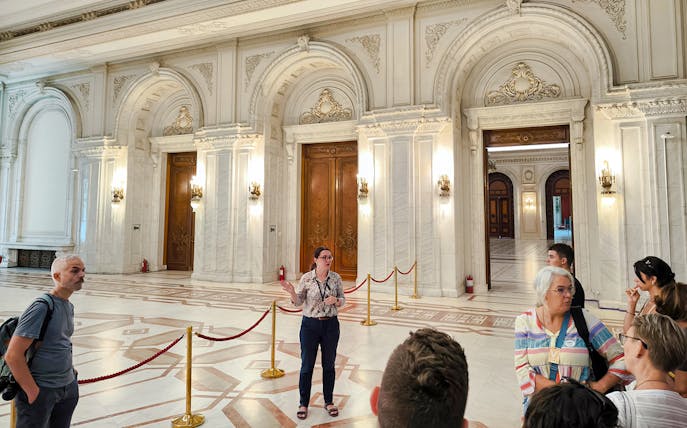 Tour guide explaining inside the ornate hall of the Palace of Parliament, Bucharest.