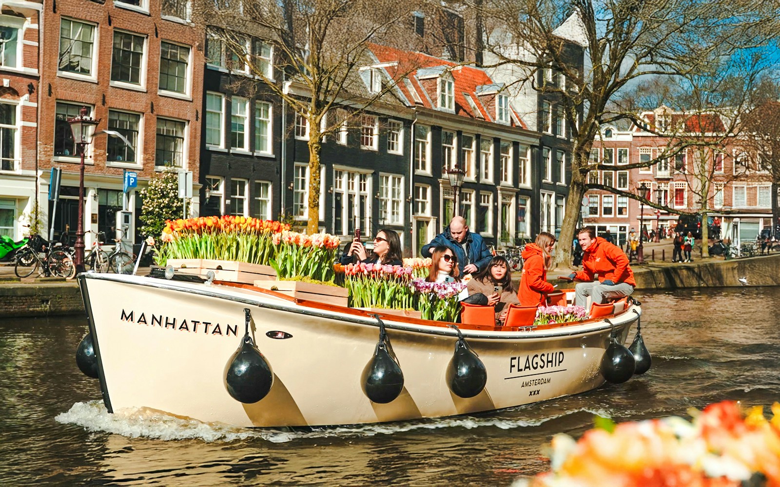 Tulip Tour boat with guests cruising through Amsterdam's scenic canals.