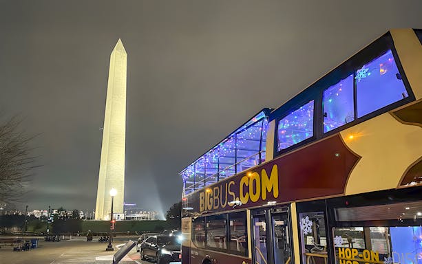 Open-top tour bus near Washington Monument during DC Holiday Tour.