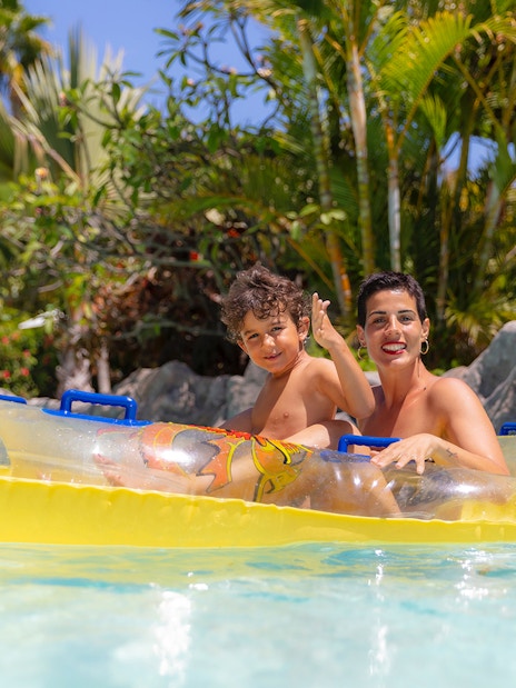 Family enjoying a lazy river ride at Siam Park, surrounded by lush tropical plants.