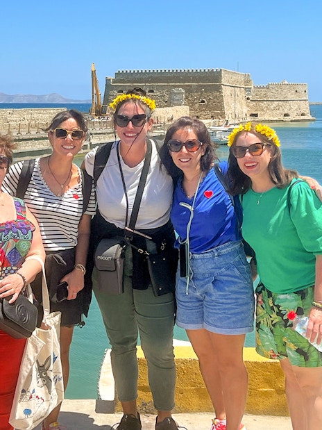 Group of tourists at Heraklion harbor with Venetian fortress in the background.