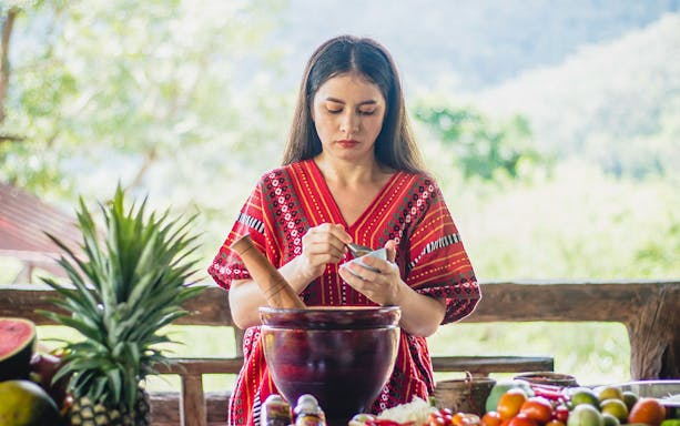 Woman preparing traditional dish at Elephant Camp with fresh ingredients.
