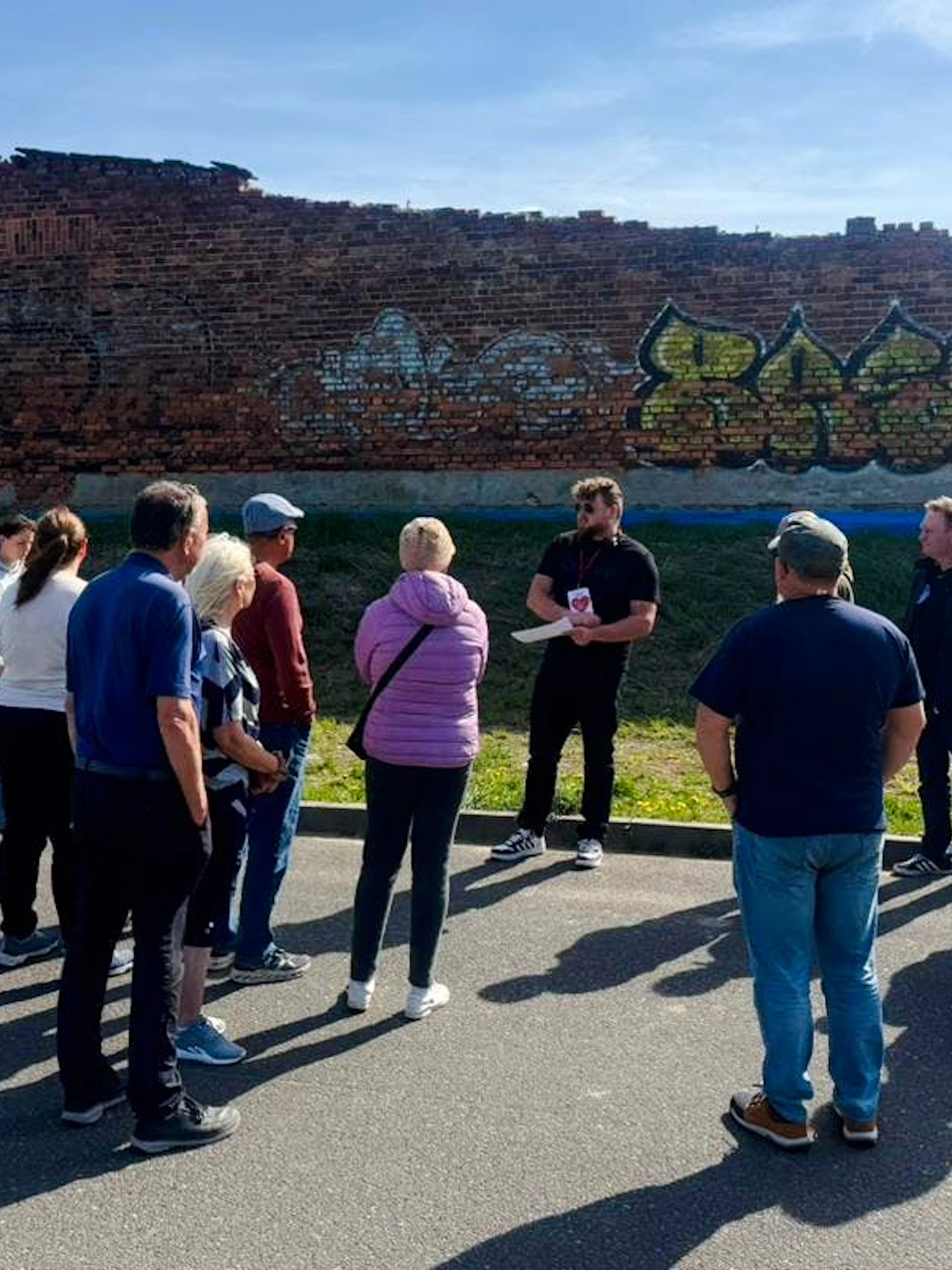 Guests listening to a guide near a brick wall during Auschwitz Outside the Walls tour.