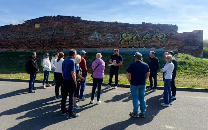 Guests listening to a guide near a brick wall during Auschwitz Outside the Walls tour.