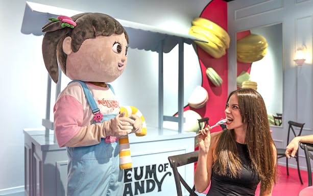 Visitor enjoying candy with cartoon character at Museum of Candy, Dubai.