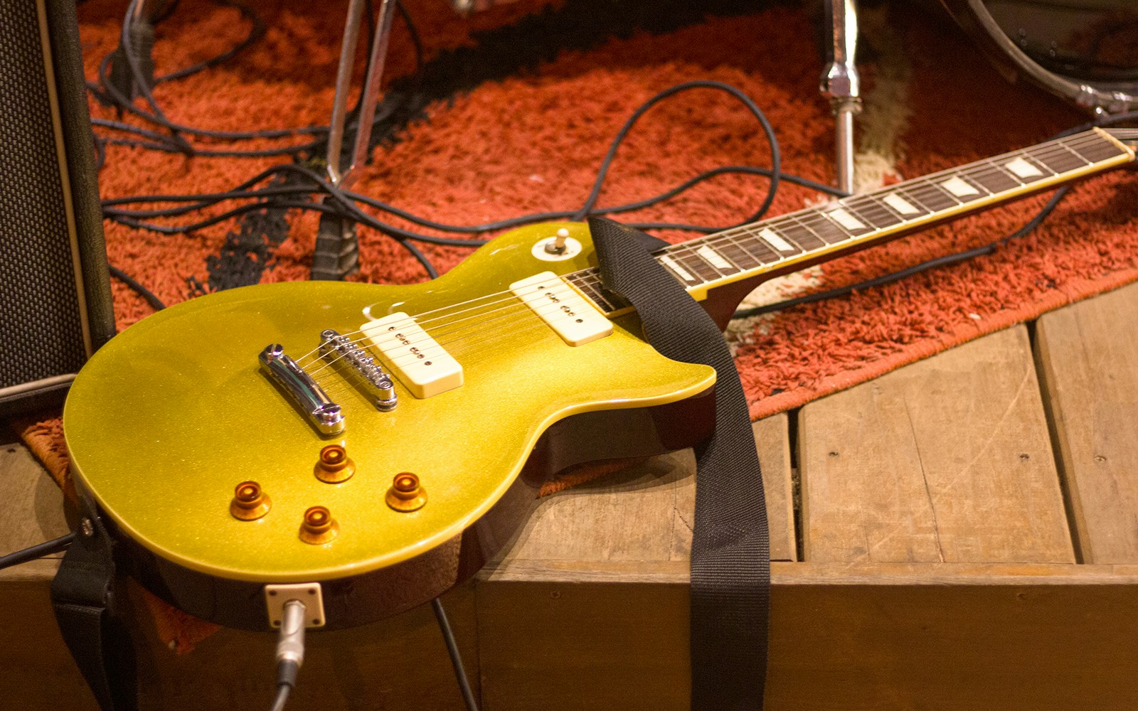 Electric guitar on stage with amplifier and cables.