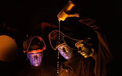 Blue Man Group performers on stage with glowing paint, Orlando.