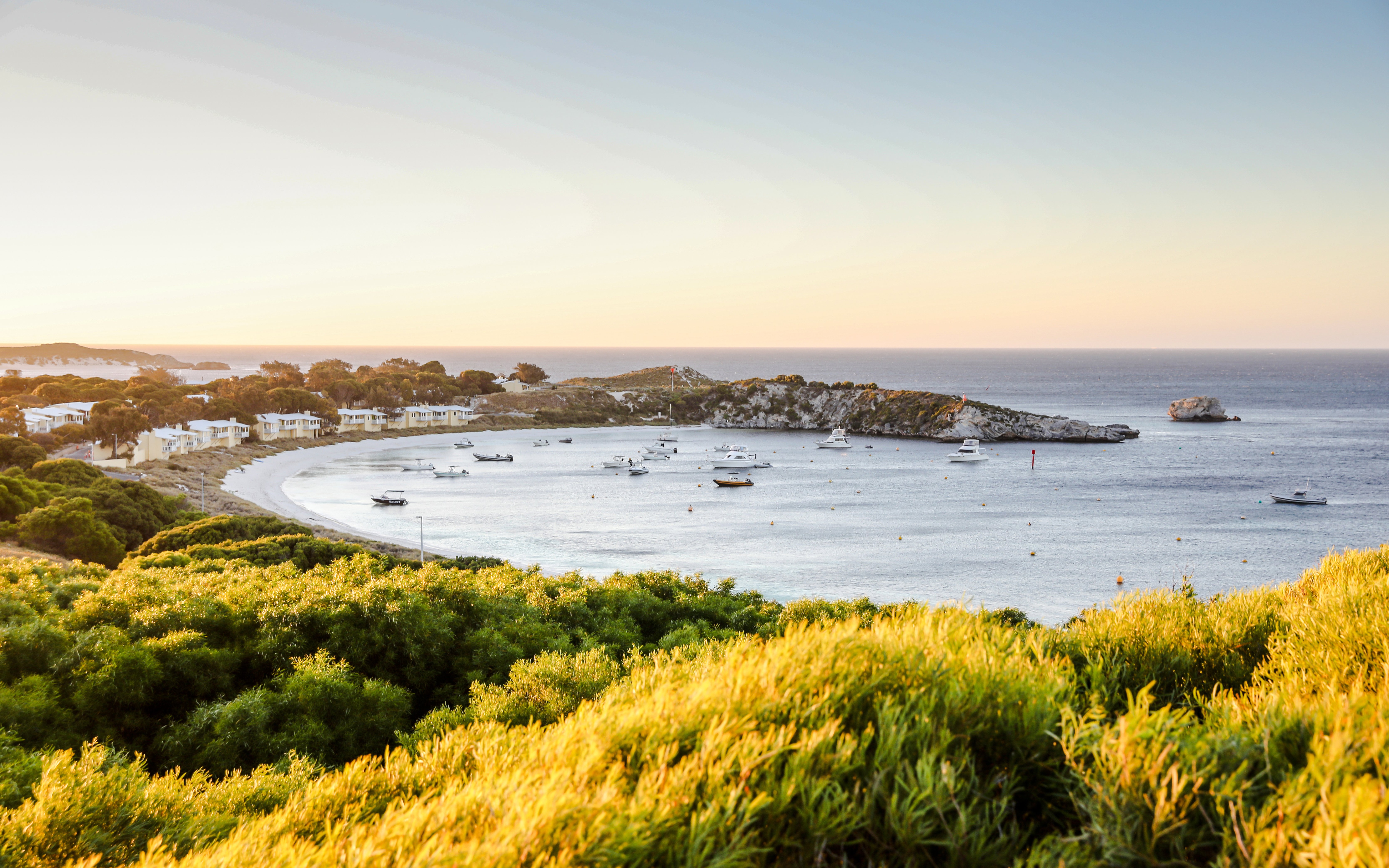 Snorkeling boats anchored in a bay near Perth with coastal landscape.