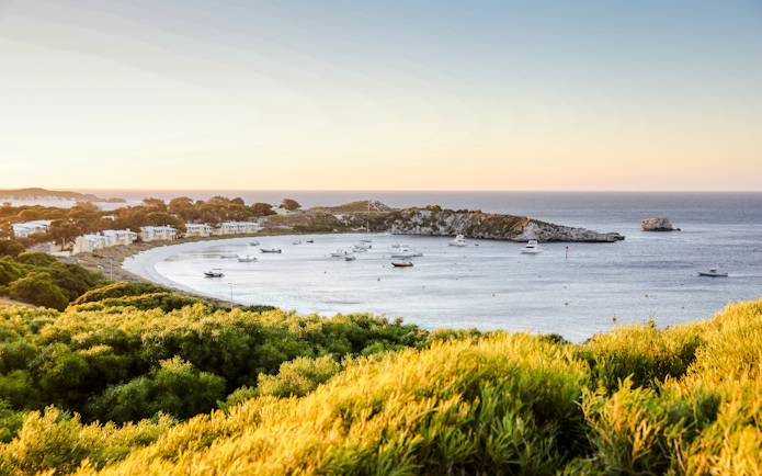 Snorkeling boats anchored in a bay near Perth with coastal landscape.