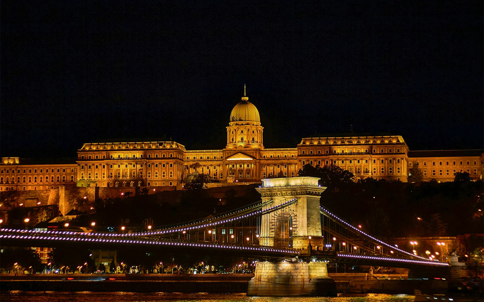 Buda Castle illuminated at night viewed from a Danube River sightseeing cruise in Budapest.