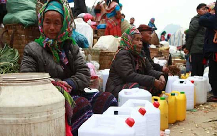Vendors at Bac Ha Market selling corn wine in plastic containers, Vietnam.