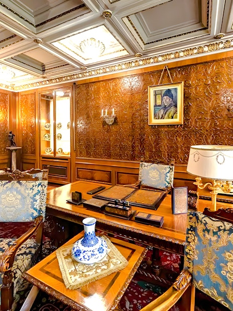 Interior of Ceaușescu Mansion in Bucharest with ornate wood paneling and vintage furniture.