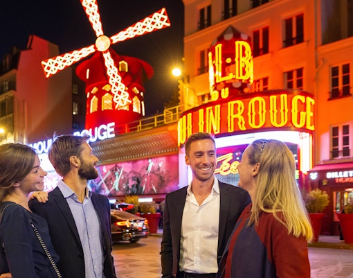 Group outside Moulin Rouge in Paris at night with iconic windmill.