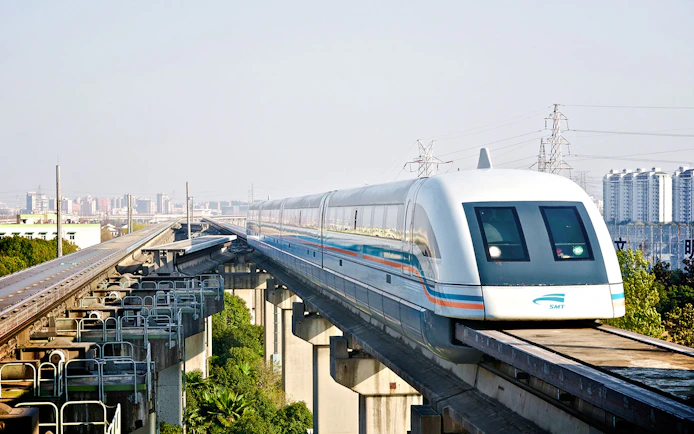 Shanghai Maglev Train on elevated track with city skyline in background.