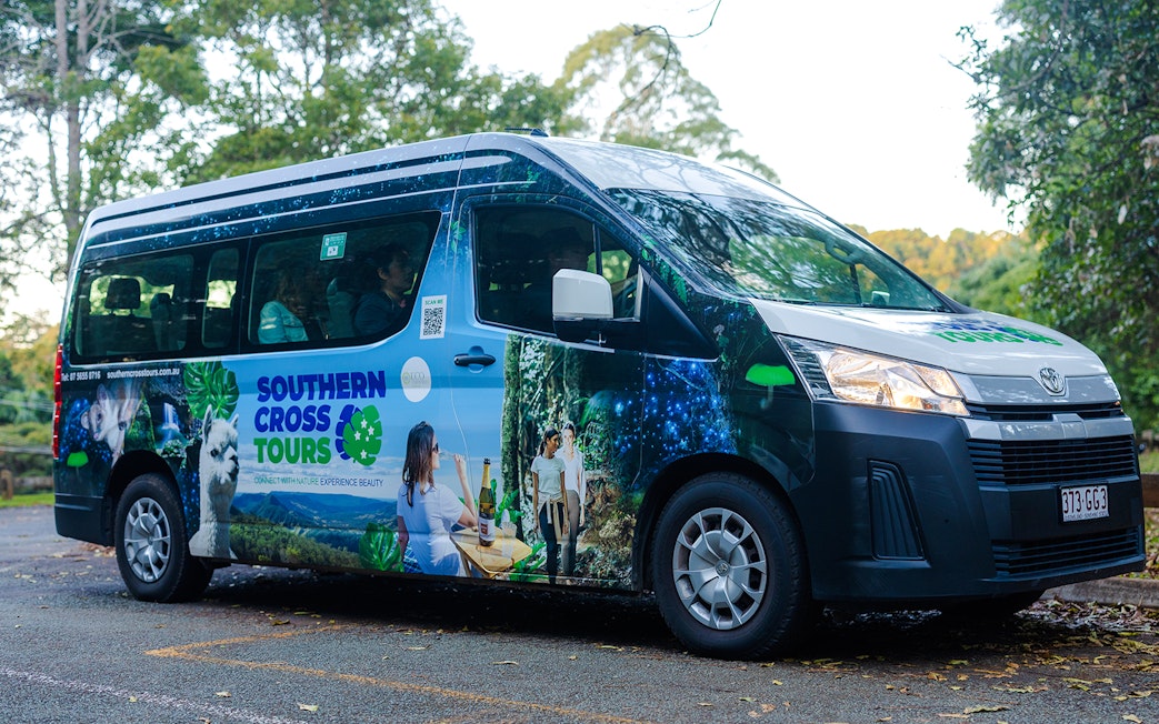 Tour van for Evening Rainforest & Glow Worm Experience parked in lush forest setting.