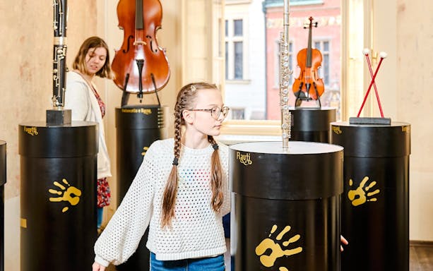 Guests interacting with musical exhibits at Mozart Interactive Museum in Prague.
