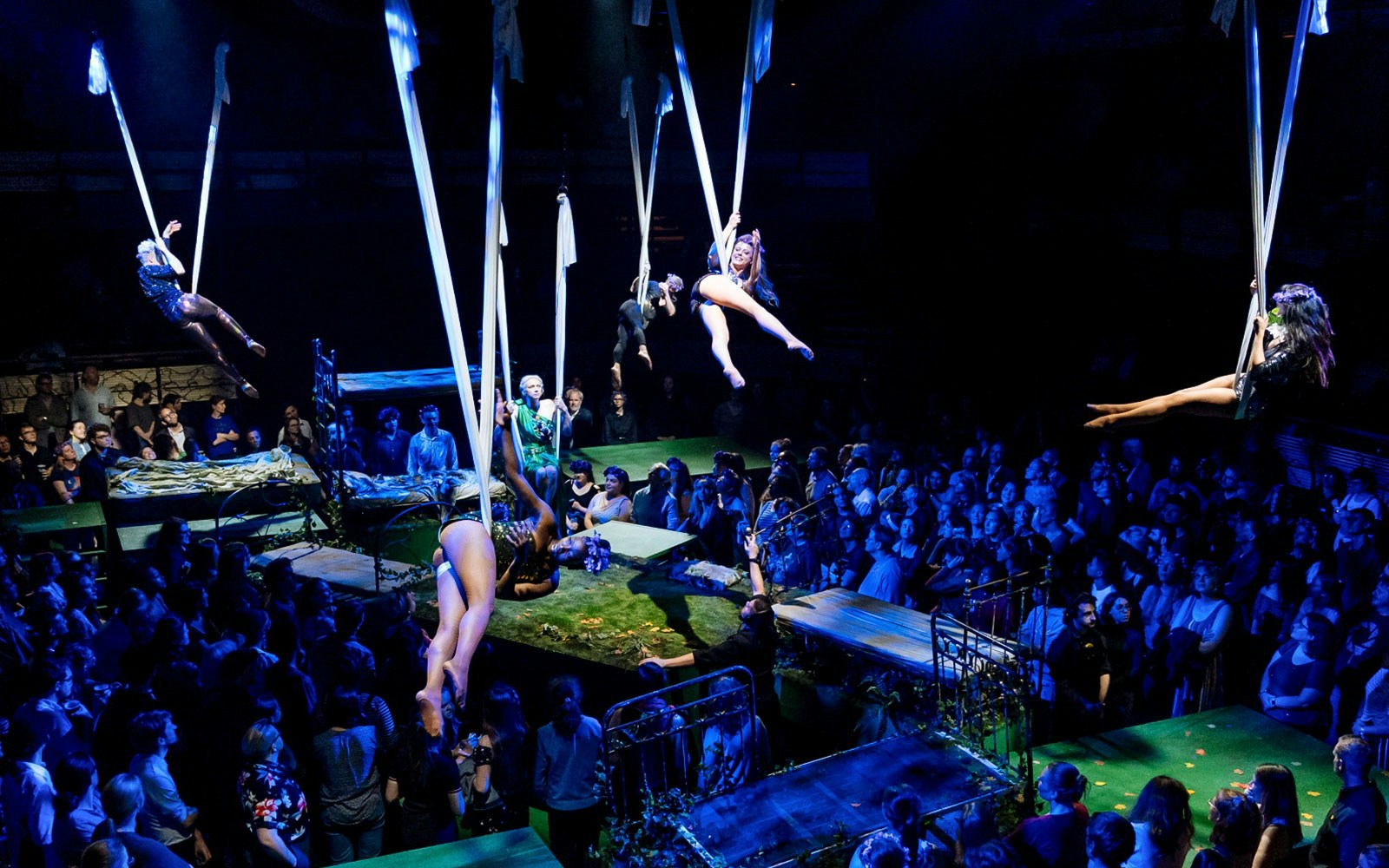 Aerial performers in a theater production of A Midsummer Night’s Dream, surrounded by an audience.