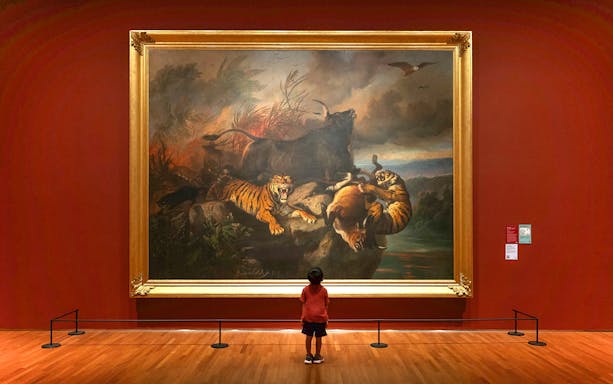 Child viewing a large painting of tigers and wildlife at National Gallery Singapore.