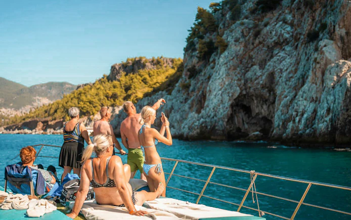 Guests relaxing on a boat, enjoying views of rocky cliffs during Alanya Boat Day Tour.