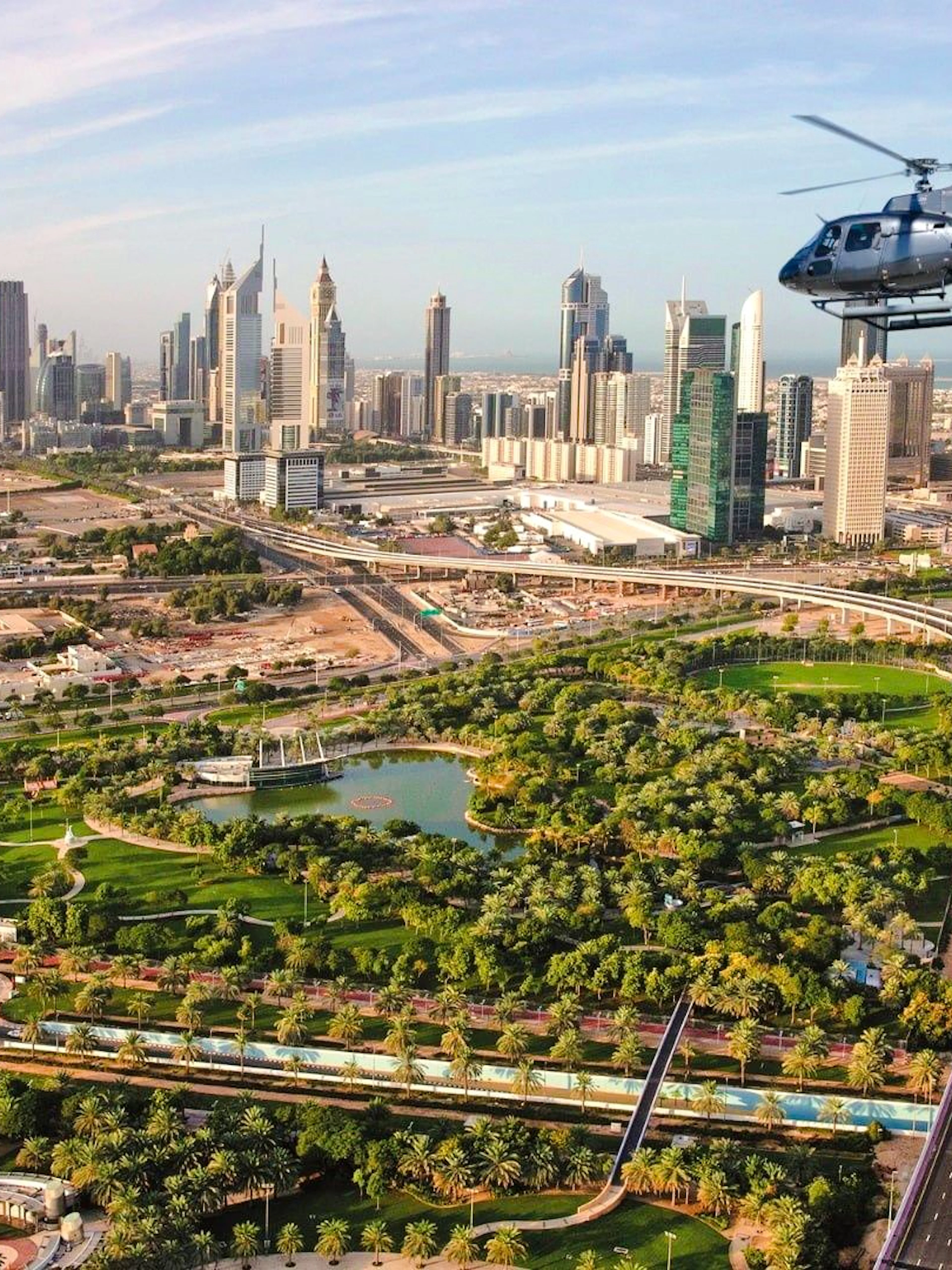 Helicopter flying over Dubai cityscape with Burj Khalifa in view.