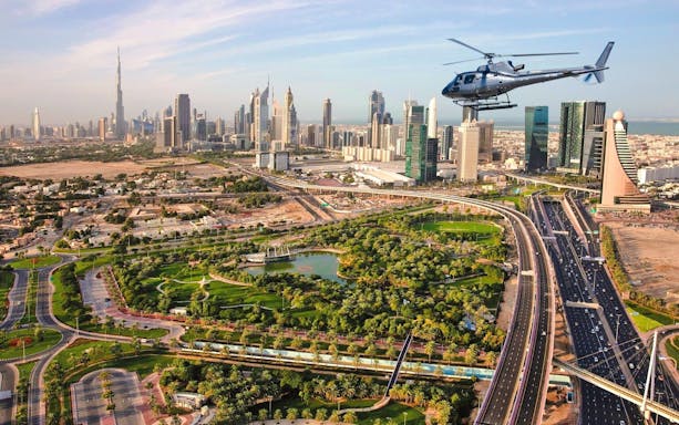 Helicopter flying over Dubai cityscape with Burj Khalifa in view.
