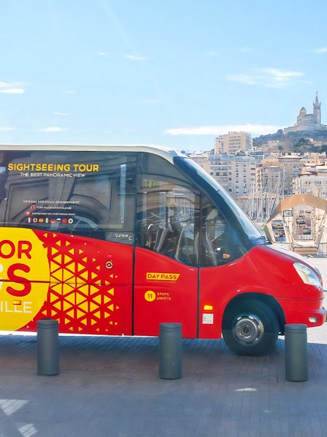 Colorbus Marseille at port with Notre-Dame de la Garde in background.