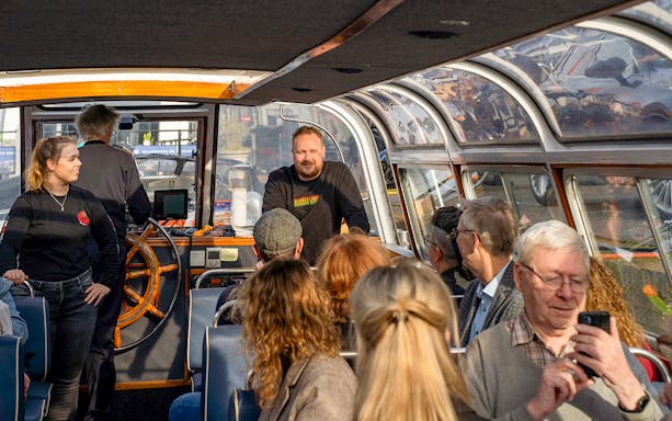 Beer tasting cruise participants listening to a guide on a boat in Haarlem.